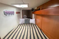 Cozy cabin interior of a 2009 Leopard 40 yacht with striped bedding and wooden accents.