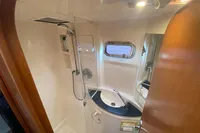 Compact bathroom in a 2009 Leopard 40 yacht, featuring a shower, sink, and porthole window.
