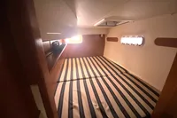 Cozy cabin interior of 2009 Leopard 40 catamaran with striped bedding and porthole windows.
