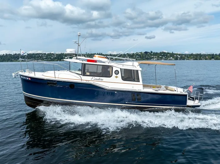 Evadere Yacht Photos Pics 2021 Ranger Tugs R-27 cruising on a lake under a cloudy sky.
