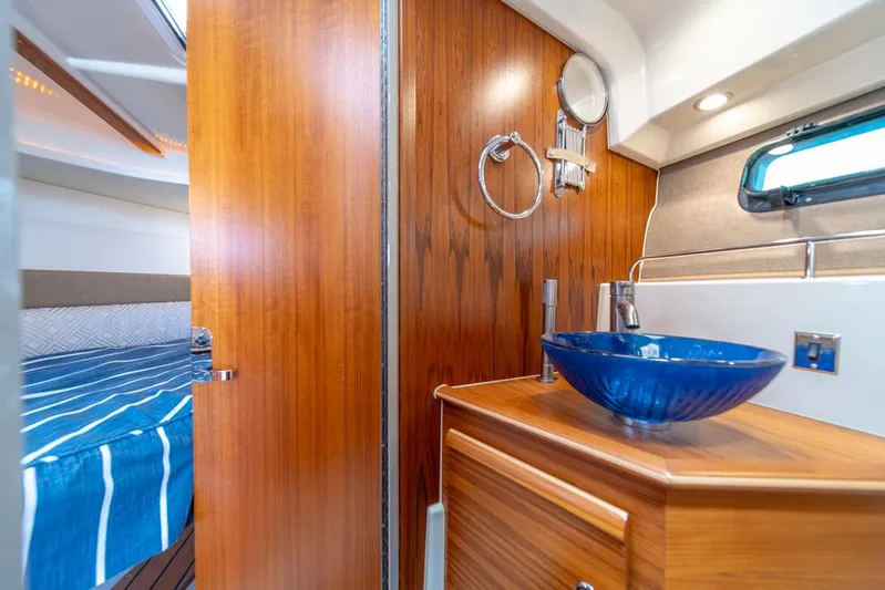 Evadere Yacht Photos Pics 2021 Ranger Tugs R-27 interior with wooden cabinetry and blue glass sink.