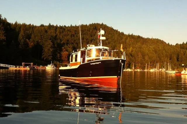 Glasgow Ranger Yacht Photos Pics 2014 Ranger Tugs R-31 boat on calm water, surrounded by forested hills.
