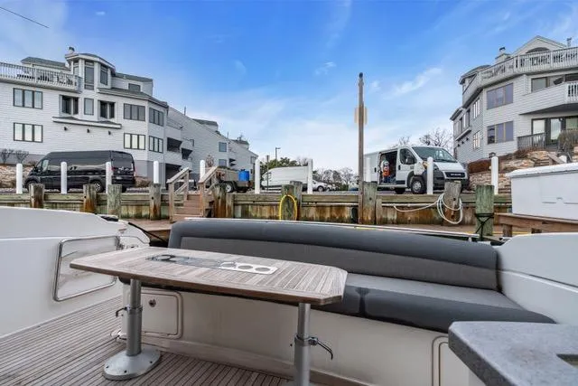 Ayeroller Yacht Photos Pics 2014 Riviera 4400 Sport Yacht docked, featuring outdoor seating and table, with waterfront homes in background.