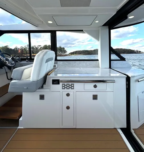 Nightingale Yacht Photos Pics 2023 Regal 36 Grande Coupe interior with helm and cabinetry, overlooking serene waters.