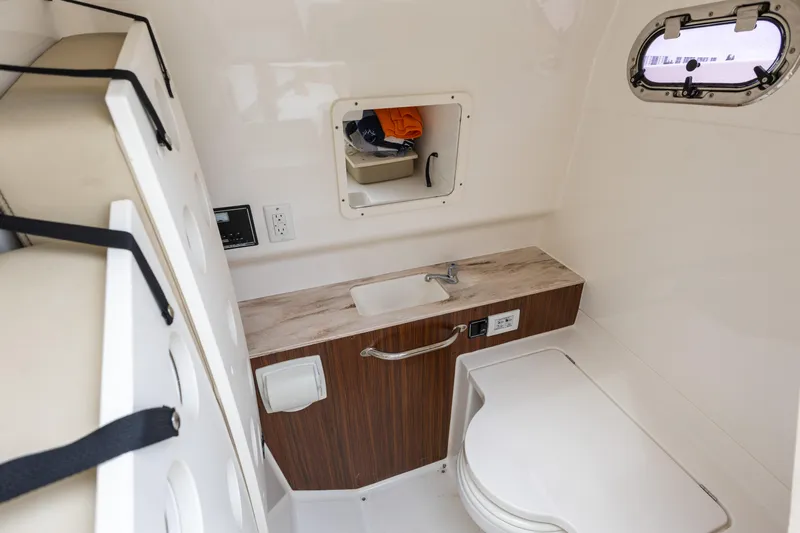 Little Perspective Yacht Photos Pics 2019 Pursuit S 288 Sport boat interior with sink, storage, and porthole window.