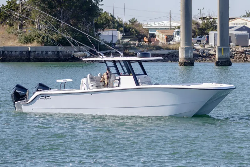  Yacht Photos Pics 2022 Invincible 33 Catamaran cruising on water near docks.