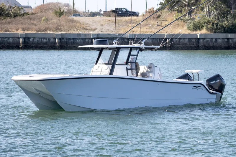  Yacht Photos Pics 2022 Invincible 33 Catamaran on water, featuring sleek design and fishing rods.