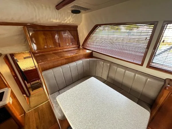  Yacht Photos Pics 2001 Bertram 39 Convertible interior with dining area, wooden cabinets, and large window blinds.