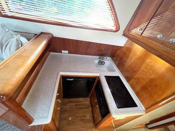  Yacht Photos Pics 2001 Bertram 39 Convertible yacht kitchen with stove, sink, and wooden cabinetry.