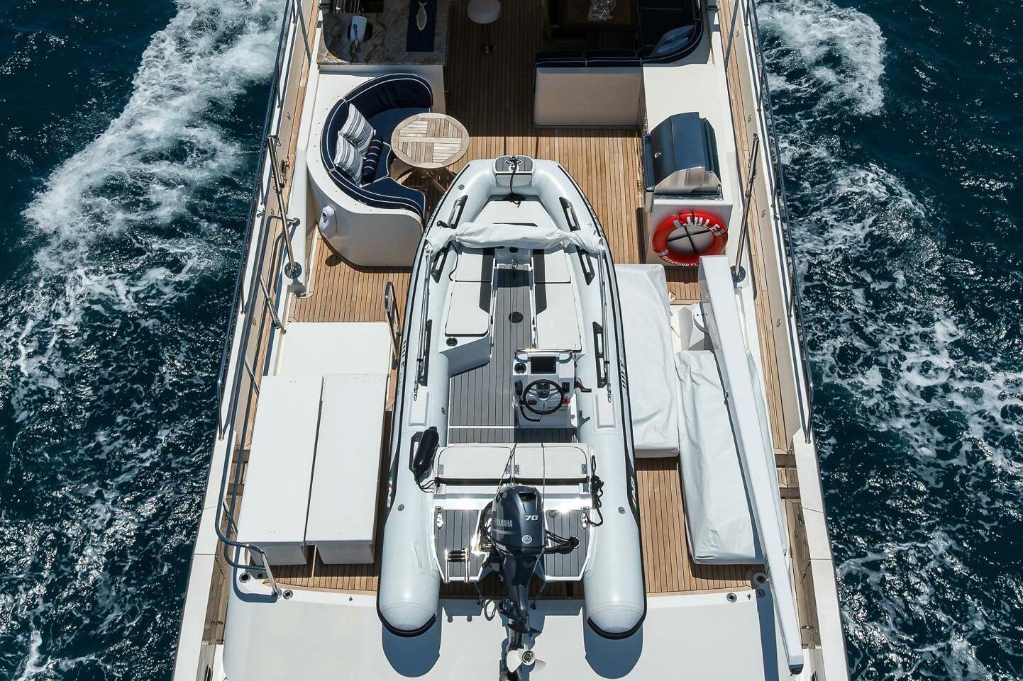 2005 Pacific Mariner 85 yacht deck with tender and seating area on open sea.