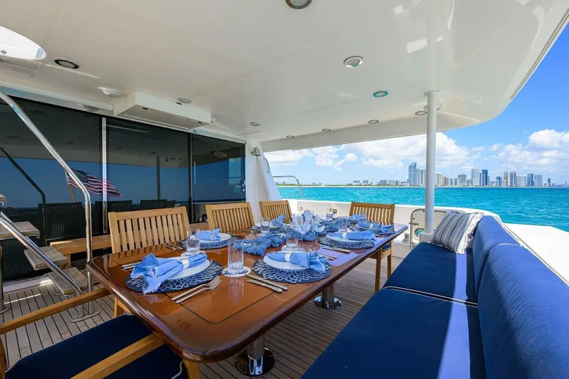 Jule Yacht Photos Pics Luxurious dining setup on 2005 Pacific Mariner 85 yacht, overlooking ocean and city skyline.