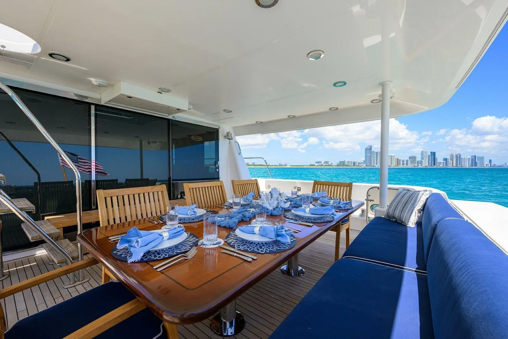 Luxurious dining setup on 2005 Pacific Mariner 85 yacht, overlooking ocean and city skyline.