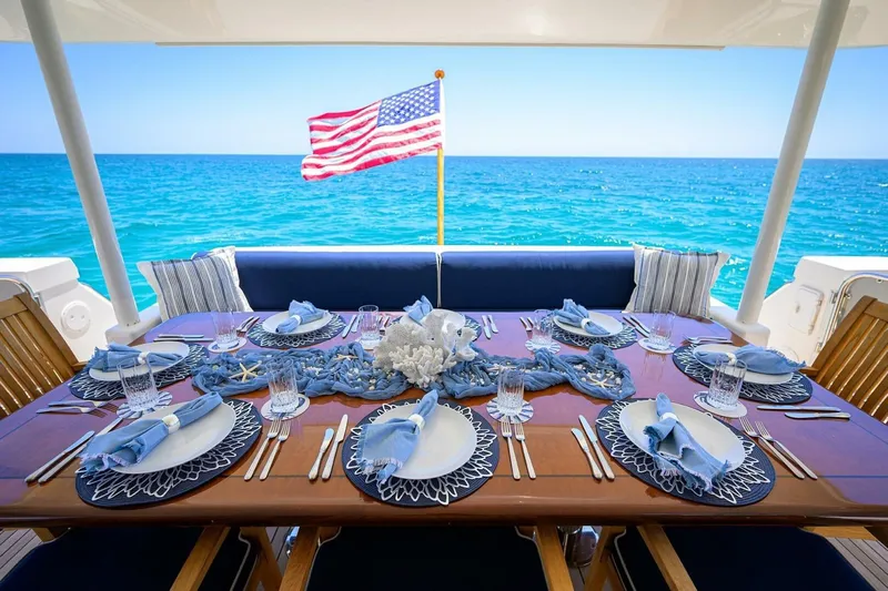 Jule Yacht Photos Pics Luxurious dining setup on 2005 Pacific Mariner 85 yacht, ocean view, American flag waving.