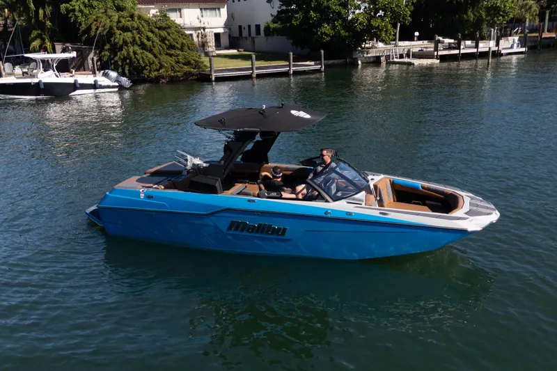  Yacht Photos Pics 2020 Malibu M240 boat cruising on a serene waterway, featuring sleek blue design.