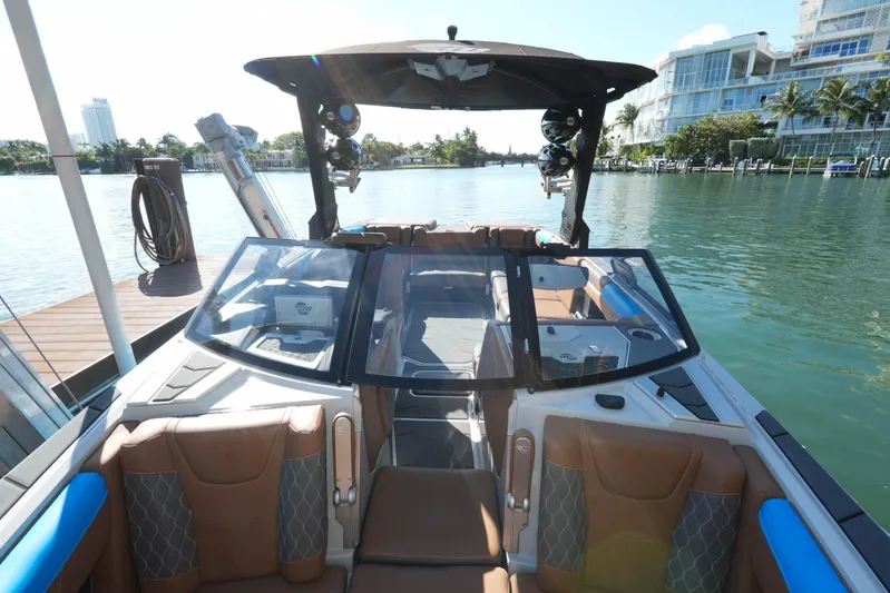  Yacht Photos Pics 2020 Malibu M240 boat interior with luxurious seating, docked by a scenic waterfront.