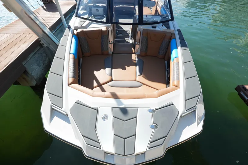  Yacht Photos Pics 2020 Malibu M240 boat with spacious seating, docked on clear water.