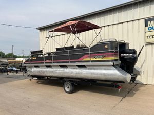 1990 Astro 24' Pontoon boat with canopy on trailer, parked outside a building.