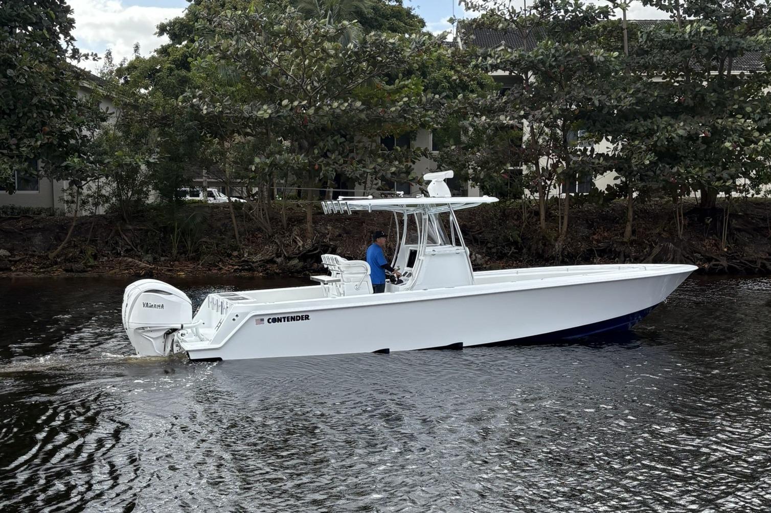 2025 Contender 32 ST boat cruising on a calm river with lush greenery.