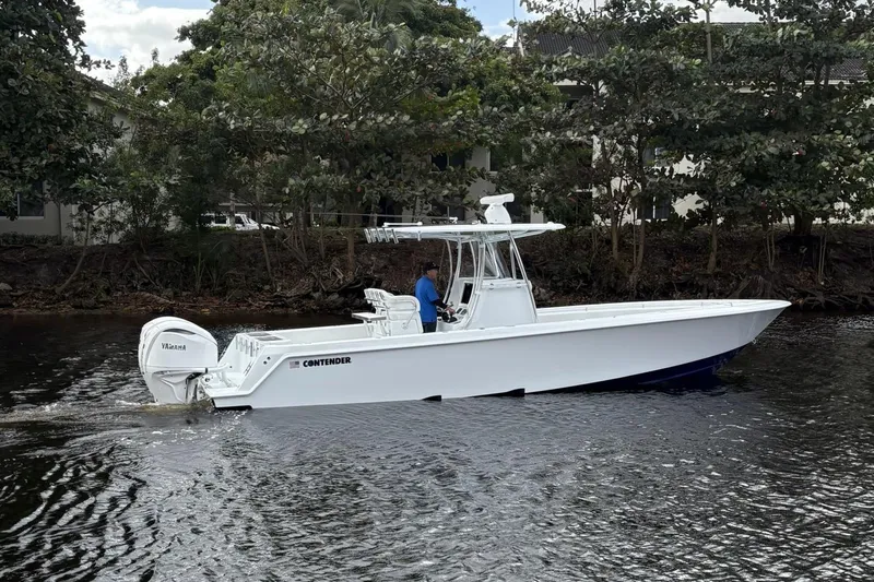  Yacht Photos Pics 2025 Contender 32 ST boat cruising on a calm river with lush greenery.