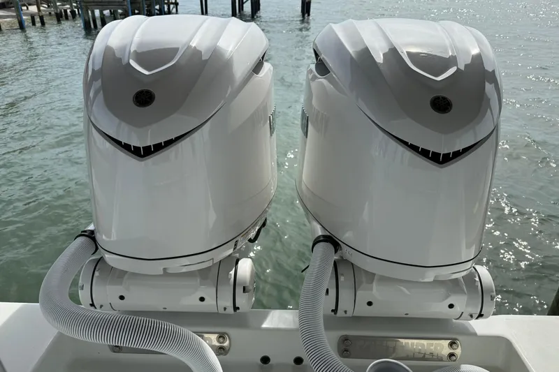  Yacht Photos Pics Twin outboard motors on a 2025 Contender 32 ST boat, docked by the water.