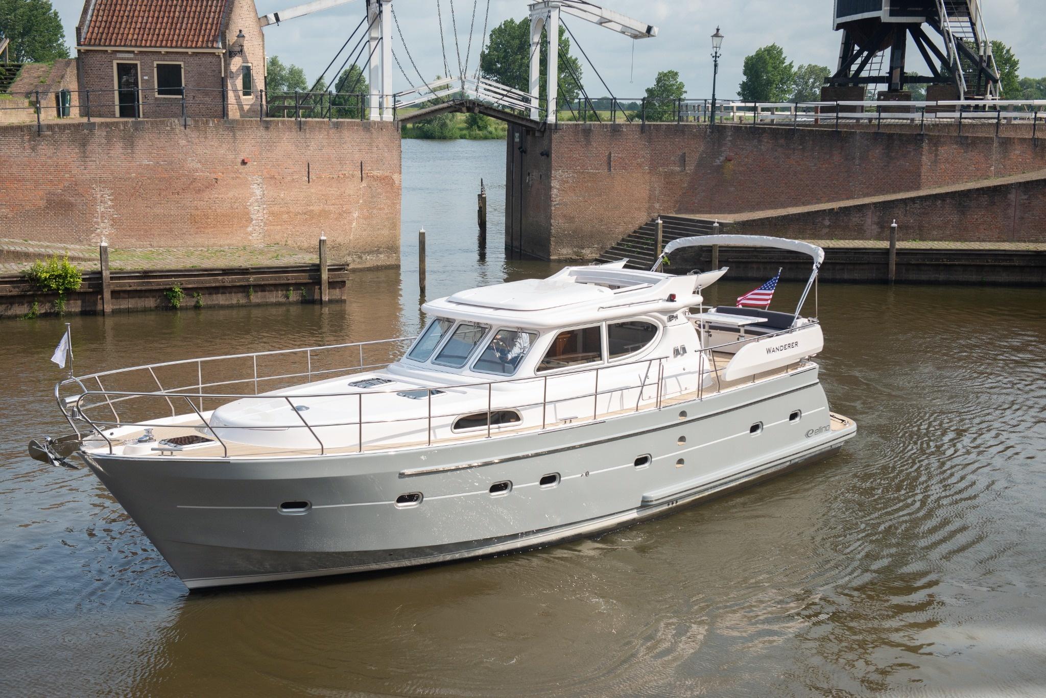 2026 Elling E4 yacht cruising near a historic brick structure on a calm river.