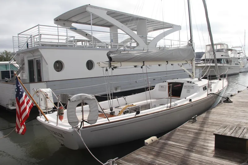 Easterly Yacht Photos Pics 2009 e Sailing Yachts e33 docked beside a large houseboat, displaying an American flag.