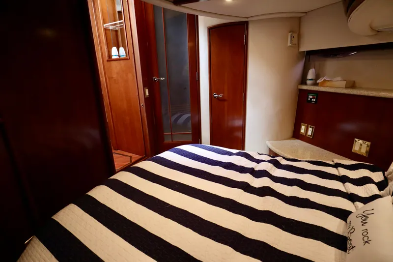 Regina Rae Yacht Photos Pics Interior of 1999 Carver 450 Voyager Pilothouse with striped bedding and wooden cabinetry.