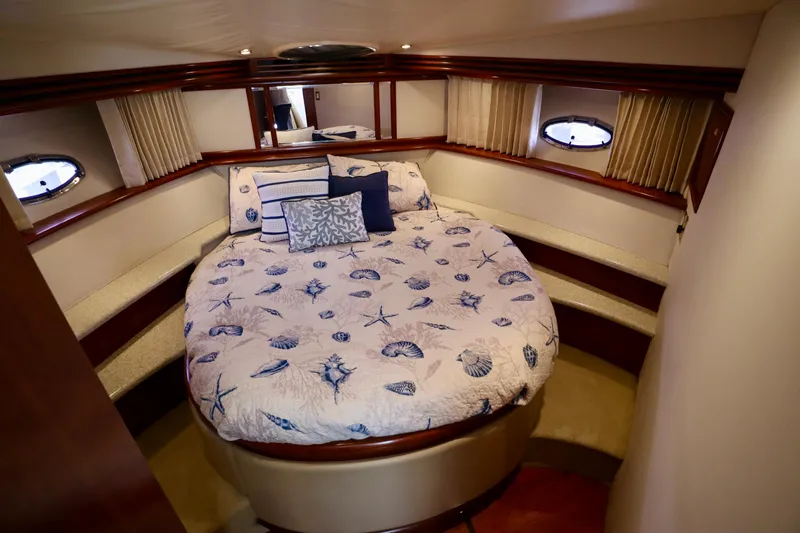 Regina Rae Yacht Photos Pics 1999 Carver 450 Voyager Pilothouse bedroom with nautical-themed bedding and porthole windows.