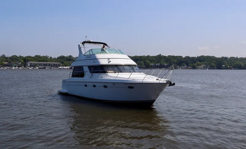 Regina Rae Yacht Photos Pics 1999 Carver 450 Voyager Pilothouse yacht on a calm lake with a scenic background.