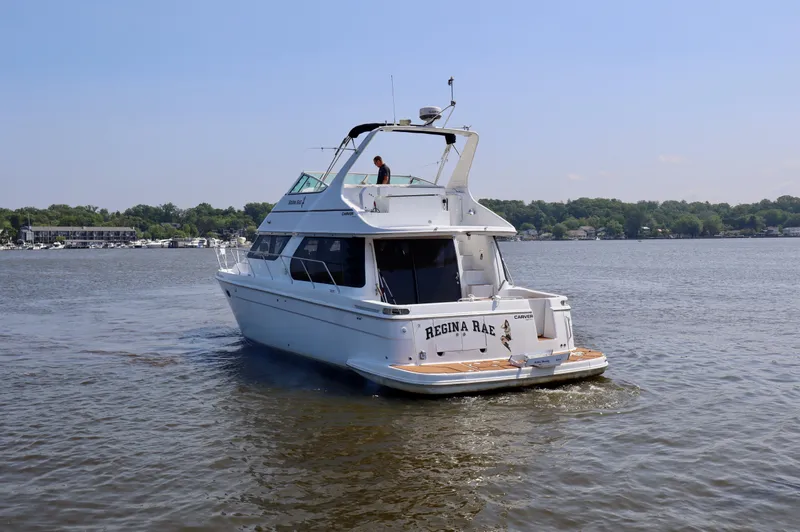 Regina Rae Yacht Photos Pics 1999 Carver 450 Voyager Pilothouse yacht on a calm lake, clear sky background.