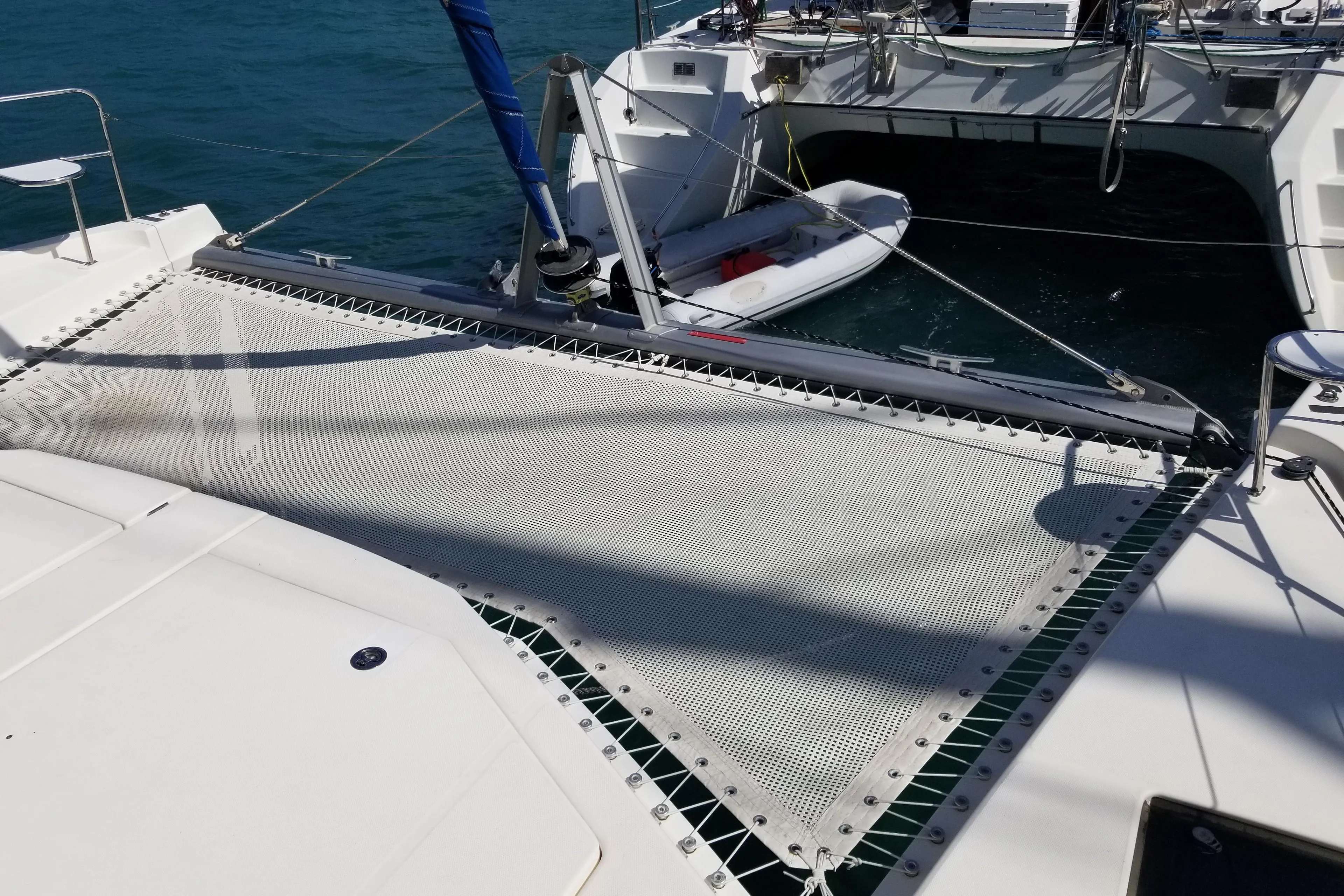 2014 Leopard 48 catamaran with netting and dinghy on blue water.