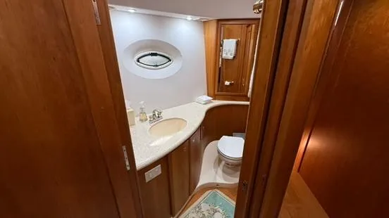 Dazilus Yacht Photos Pics 2001 Silverton 410 Sport Bridge bathroom with wooden cabinetry and oval window.