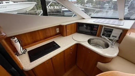 Dazilus Yacht Photos Pics 2001 Silverton 410 Sport Bridge yacht kitchen with stove, sink, and wood cabinetry.