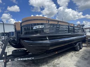 2024 Regency 250 LE3 Sport pontoon boat on trailer under a cloudy sky.
