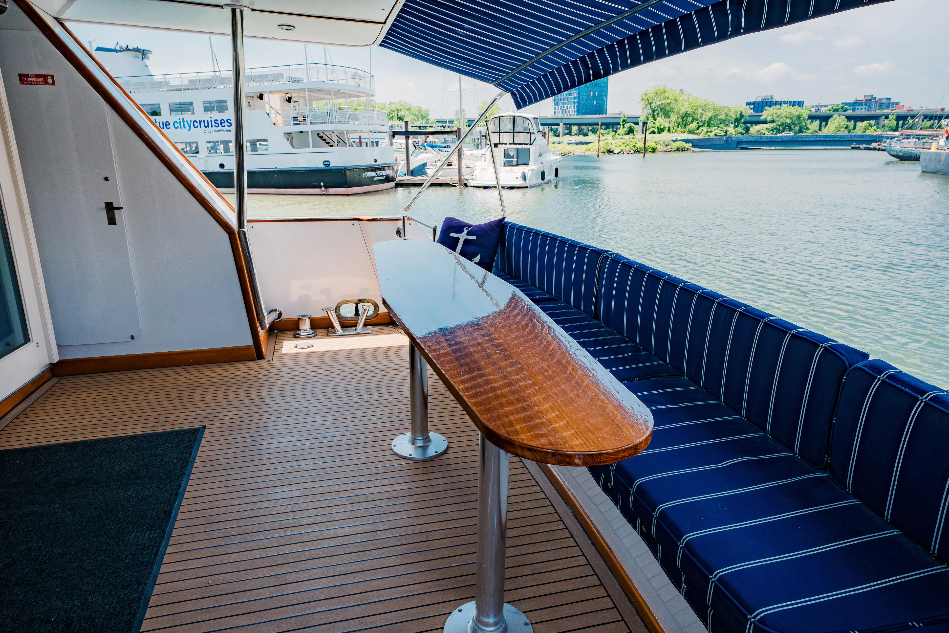 Justine Yacht Photos Pics Luxurious 1987 Guy Couach 97 yacht deck with striped seating and wooden table.