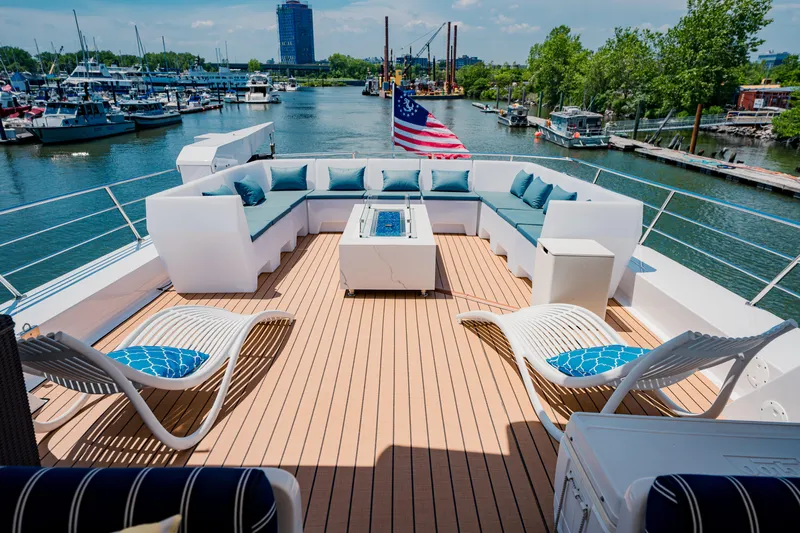 Justine Yacht Photos Pics Luxurious 1987 Guy Couach 97 yacht deck with seating, American flag, and waterfront view.