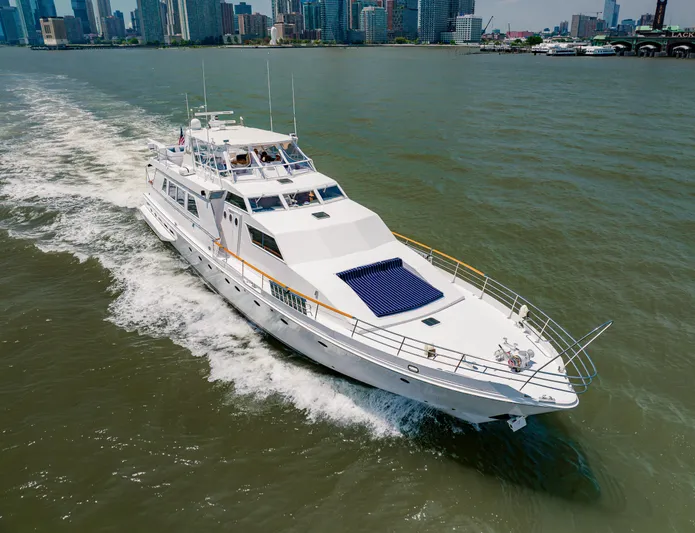 Justine Yacht Photos Pics Luxury yacht cruising on water, Guy Couach 97 model, 1987, with city skyline backdrop.