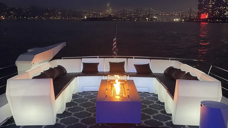 Justine Yacht Photos Pics Luxurious 1987 Guy Couach 97 yacht deck with cozy seating and fire pit, city skyline backdrop.