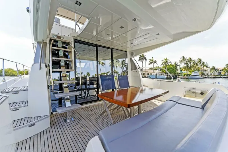 Never Enough Yacht Photos Pics Prestige 550 Flybridge 2013 yacht deck with seating, table, and stairs, overlooking marina.