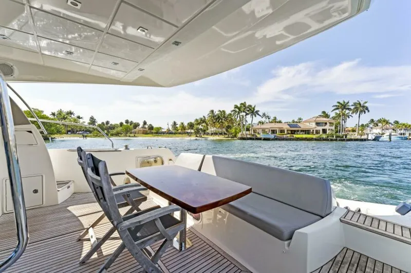 Never Enough Yacht Photos Pics Prestige 550 Flybridge 2013 yacht deck with seating, overlooking scenic waterfront and palm trees.