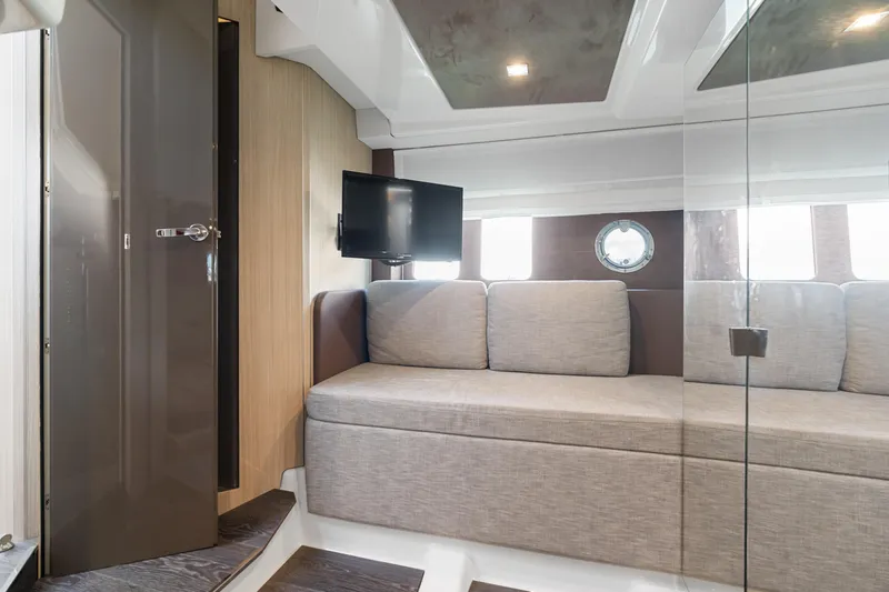  Yacht Photos Pics 2023 Cranchi M44HT yacht interior with sofa, TV, and porthole window.
