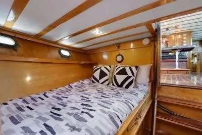 Flamingo Yacht Photos Pics 1950 Monk Pilothouse interior with cozy wooden cabin and patterned bedding.