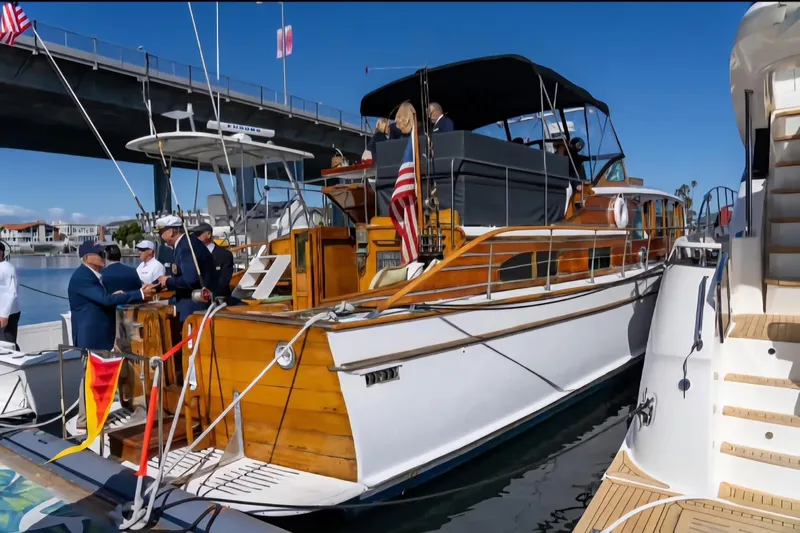 Flamingo Yacht Photos Pics 1950 Monk Pilothouse boat docked, featuring wooden details and American flag, with people onboard.