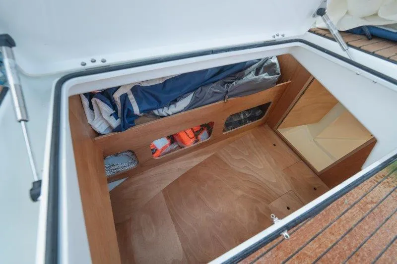  Yacht Photos Pics Storage compartment of 2025 Jeanneau Sun Odyssey 350 sailboat, featuring organized space and wooden finish.