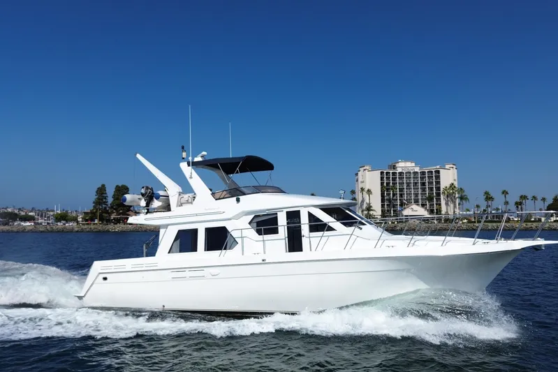 Barkruiser Yacht Photos Pics 1998 Navigator 4800 yacht cruising on water near a hotel and palm trees.