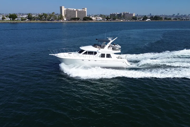 Barkruiser Yacht Photos Pics 1998 Navigator 4800 yacht cruising on a sunny day near a coastal cityscape.