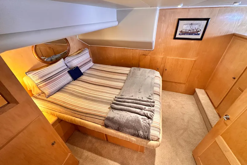 Barkruiser Yacht Photos Pics Cozy bedroom in 1998 Navigator 4800 yacht with striped bedding and wooden paneling.