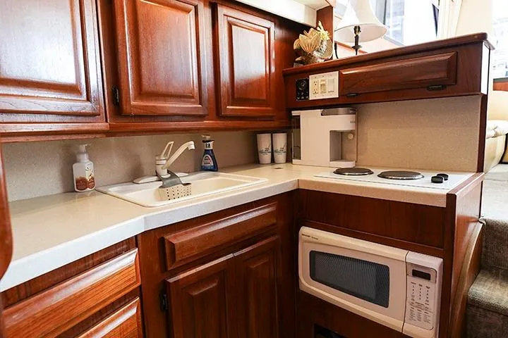 Impulse Yacht Photos Pics 1987 Viking Palm Beach yacht kitchen with wooden cabinets, sink, stove, and microwave.