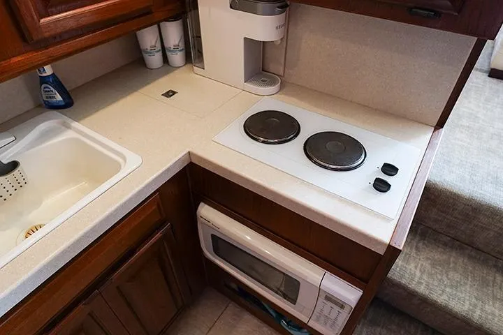 Impulse Yacht Photos Pics Compact kitchen in a 1987 Viking Palm Beach boat with stove, sink, and microwave.