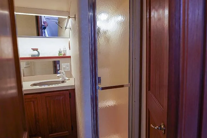 Impulse Yacht Photos Pics 1987 Viking Palm Beach yacht bathroom with sink, mirror, and shower.